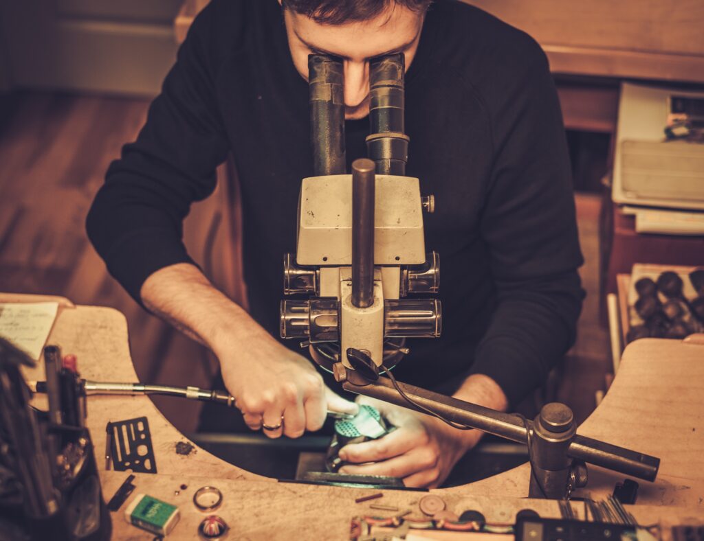 Jeweler looking at the ring through microscope in a workshop.