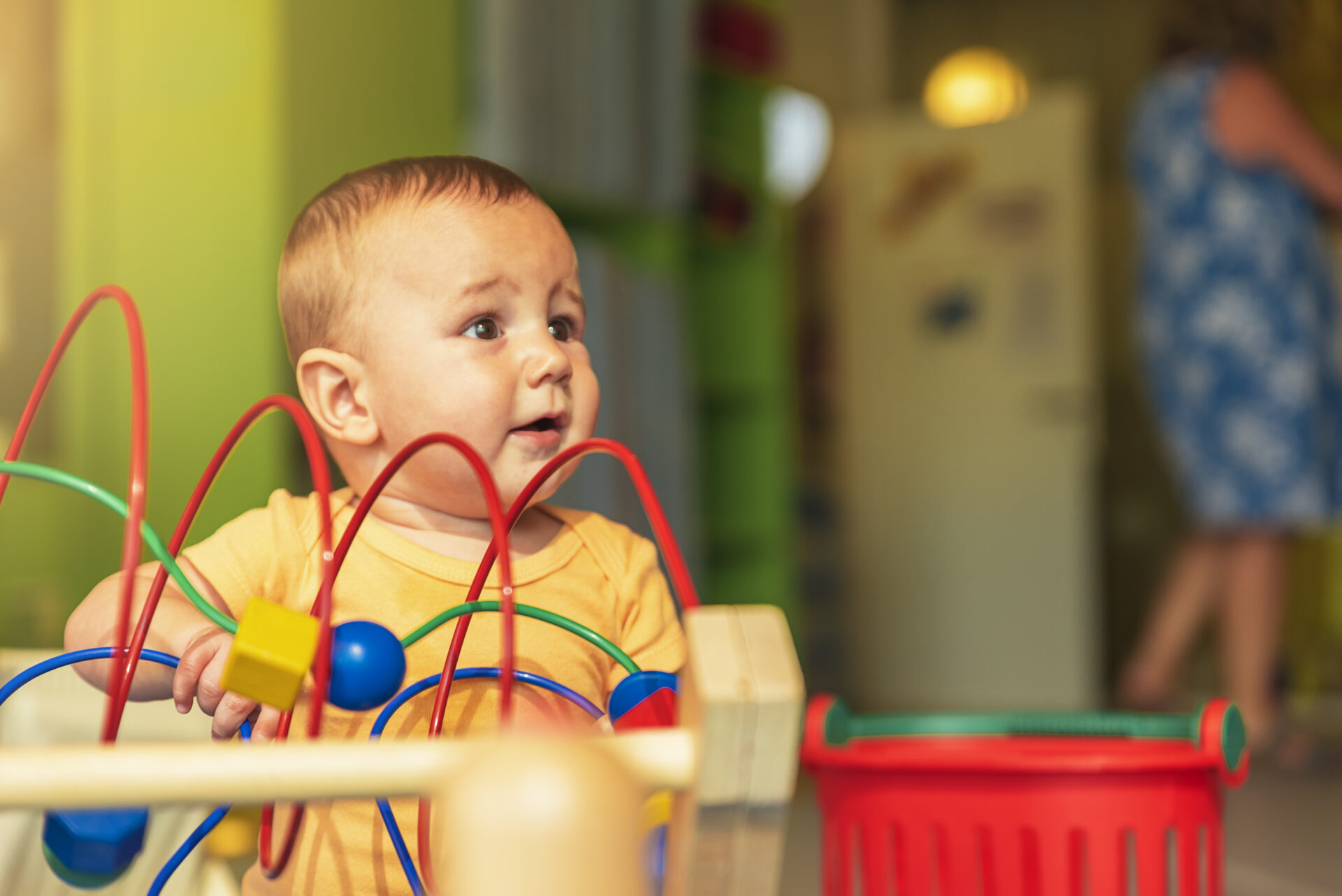 Happy baby playing with toy blocks in the kindergarten.