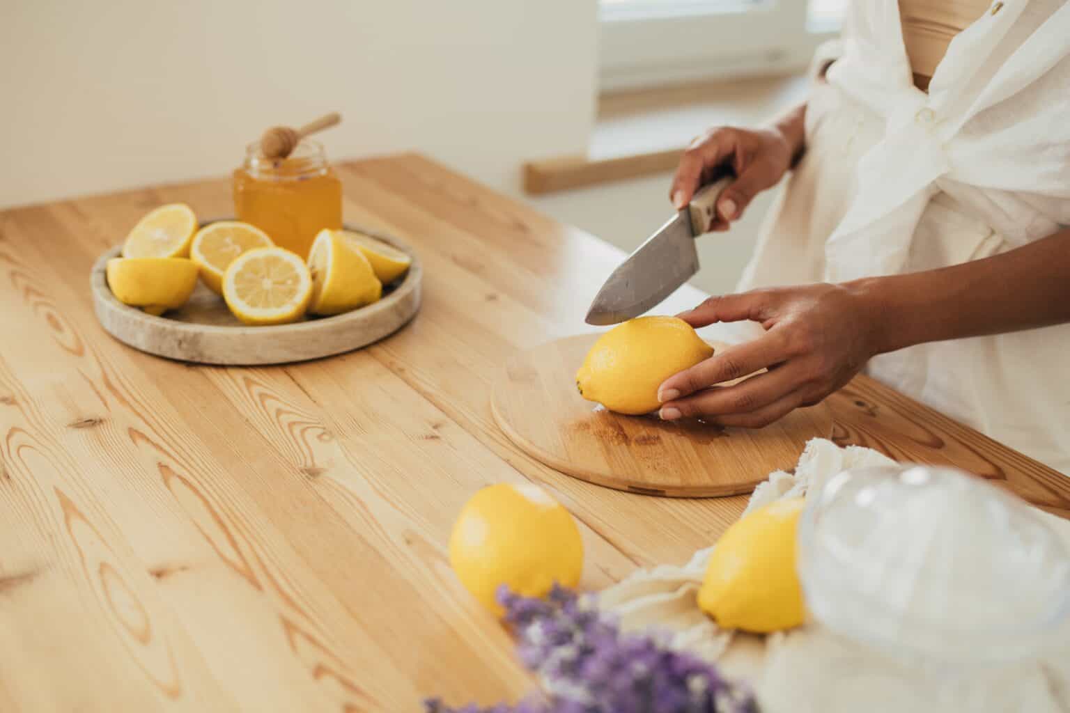 Young woman making lemonade in a kitchen of cozy house. Homemade healthy drink. Grow Citrus Indoors